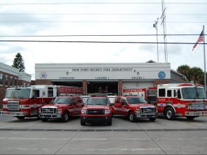 White and Brick fire station with 2 fire engines and 3 red trucks